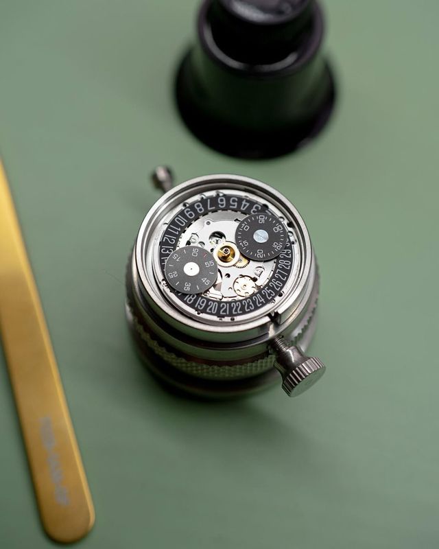 Watch movement exposed on a workbench with tweezers and loupe, showing the intricate mechanics behind authentication